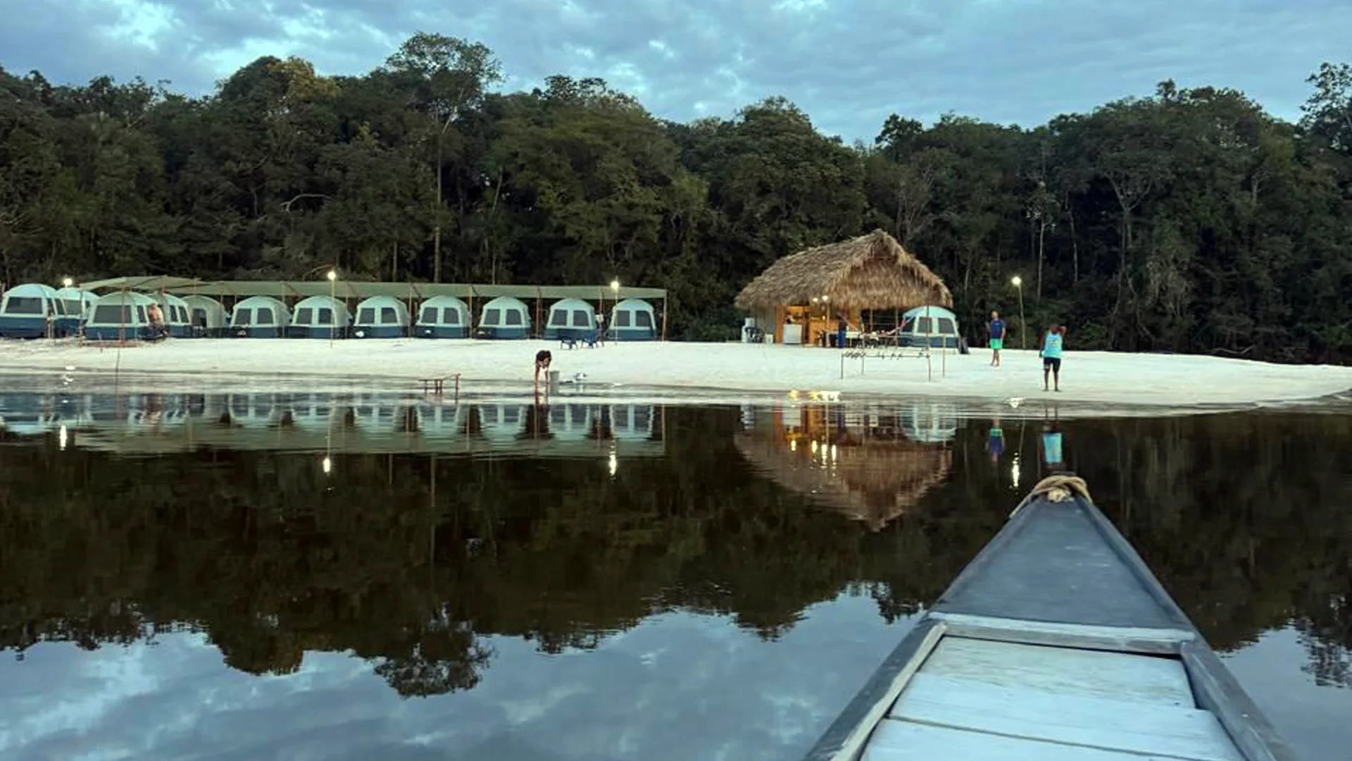 The Mataven Camp is located on a river beach, with single-occupancy tents beneath a thatched shelter on a sandy beach.